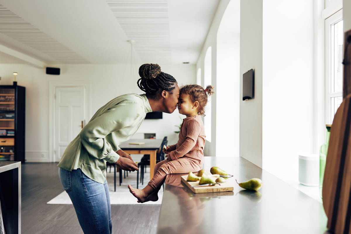 Mère embrassant une petite fille assise sur un plan de travail