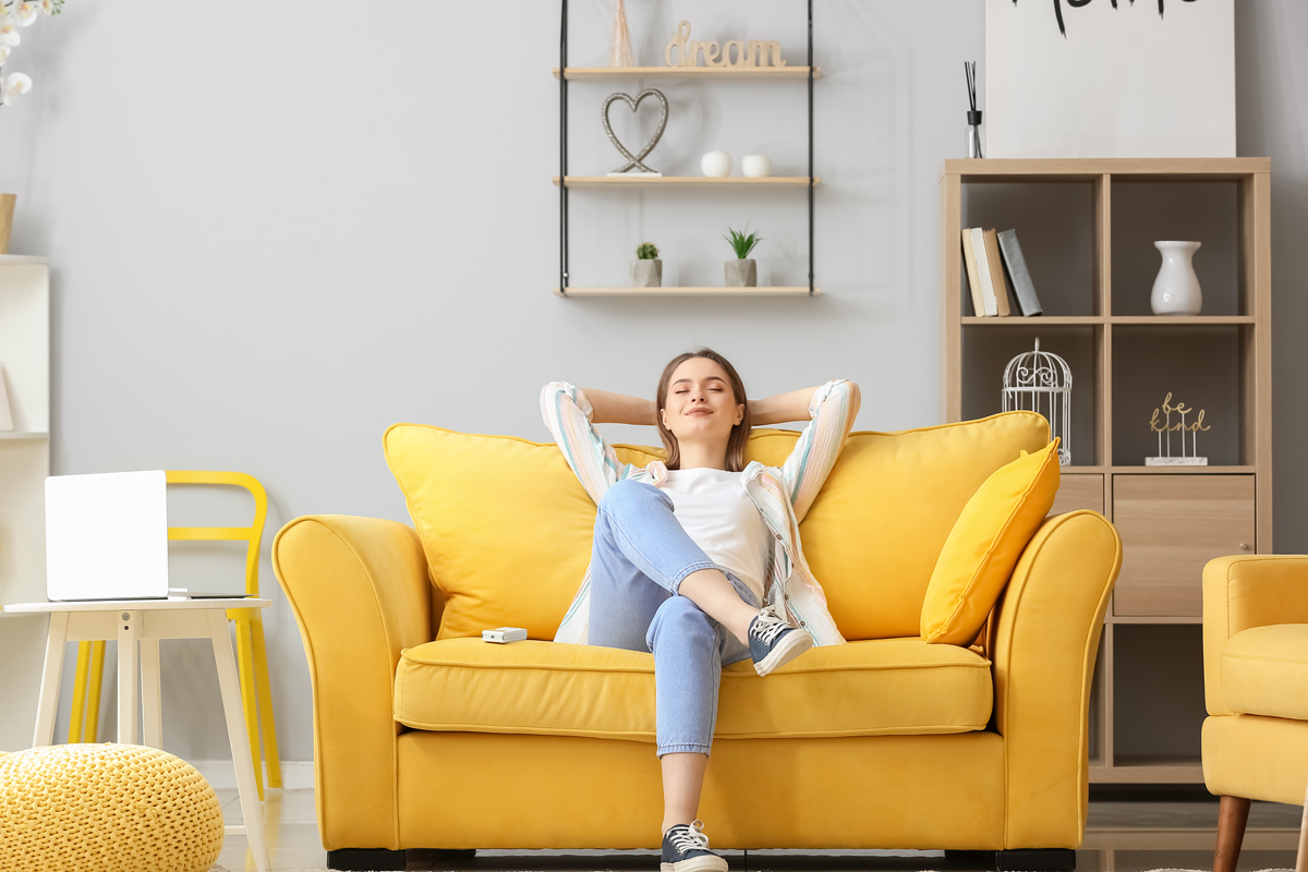 Femme seraine assise dans un canapé jaune