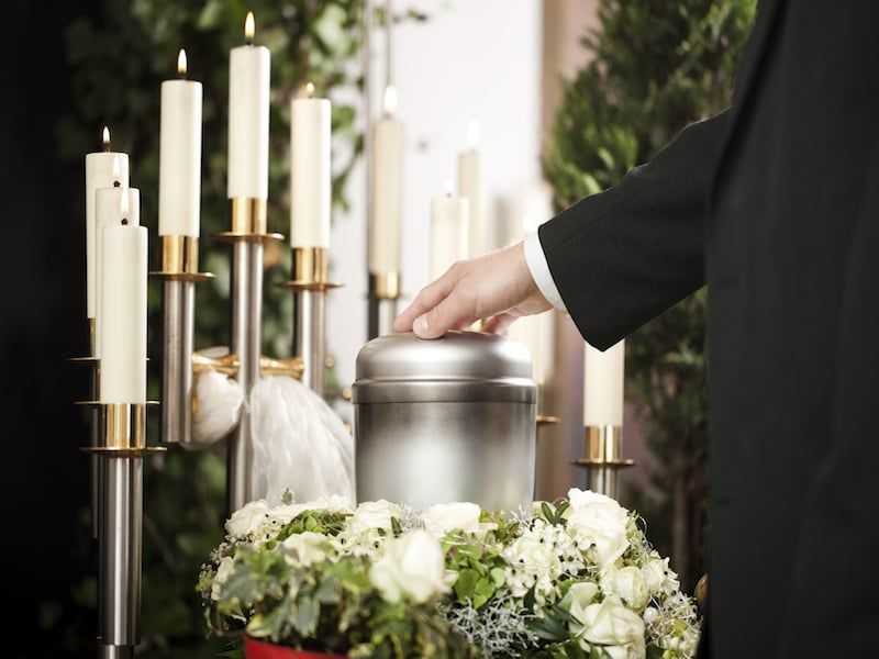 Un hombre coloca una urna en un candelabro en un funeral.