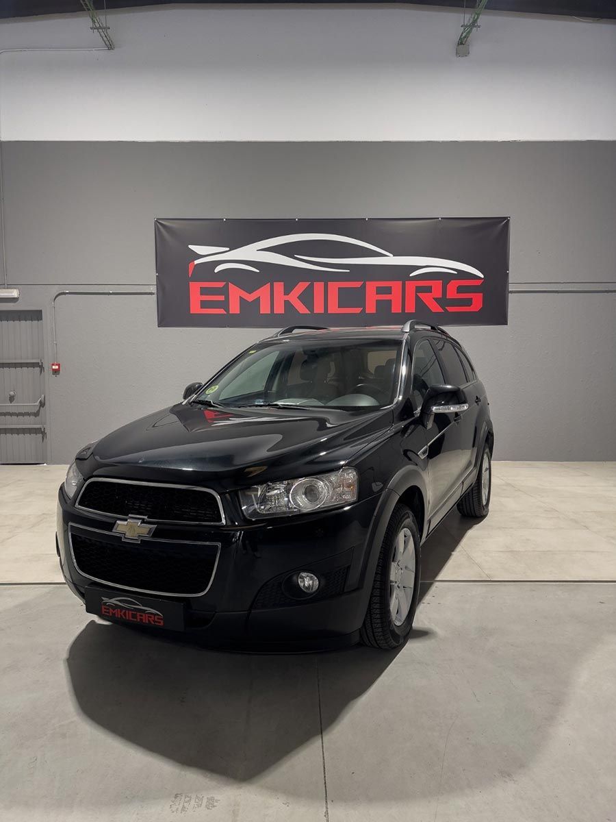 SUV negro expuesto en el interior de una sala de exposición con una pancarta de EMKICARS al fondo.