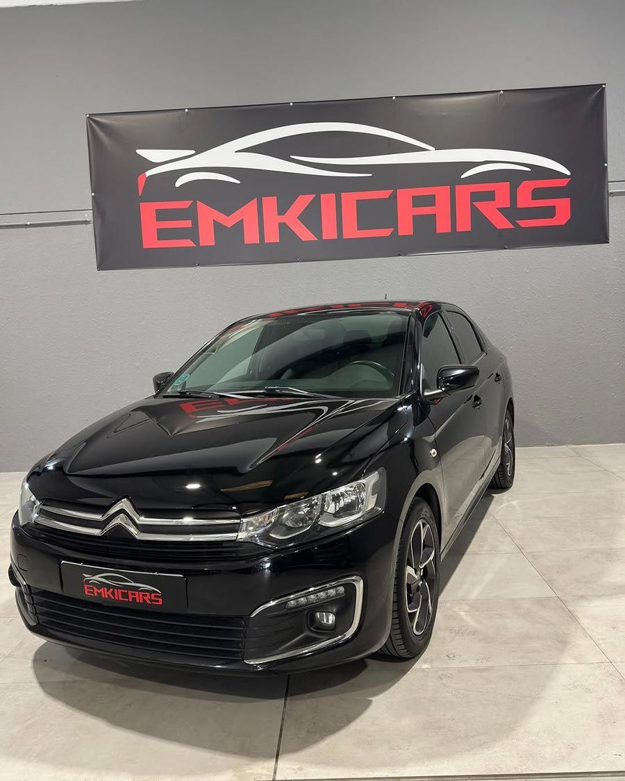 SUV negro expuesto en una sala de exhibición con una pancarta de Emkicars detrás.