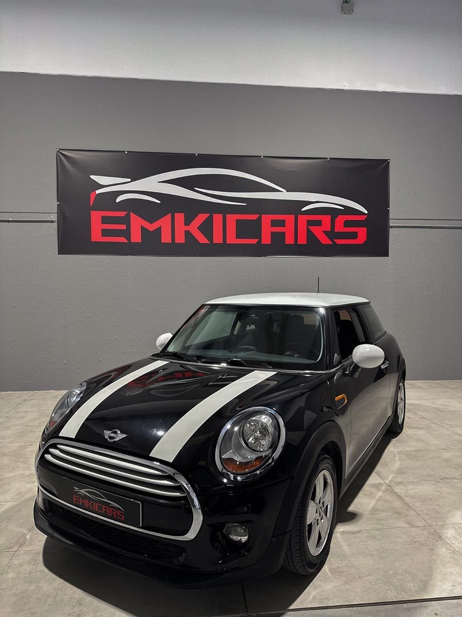 Mini Cooper negro en una sala de exposición bajo una pancarta de EMKICARS.