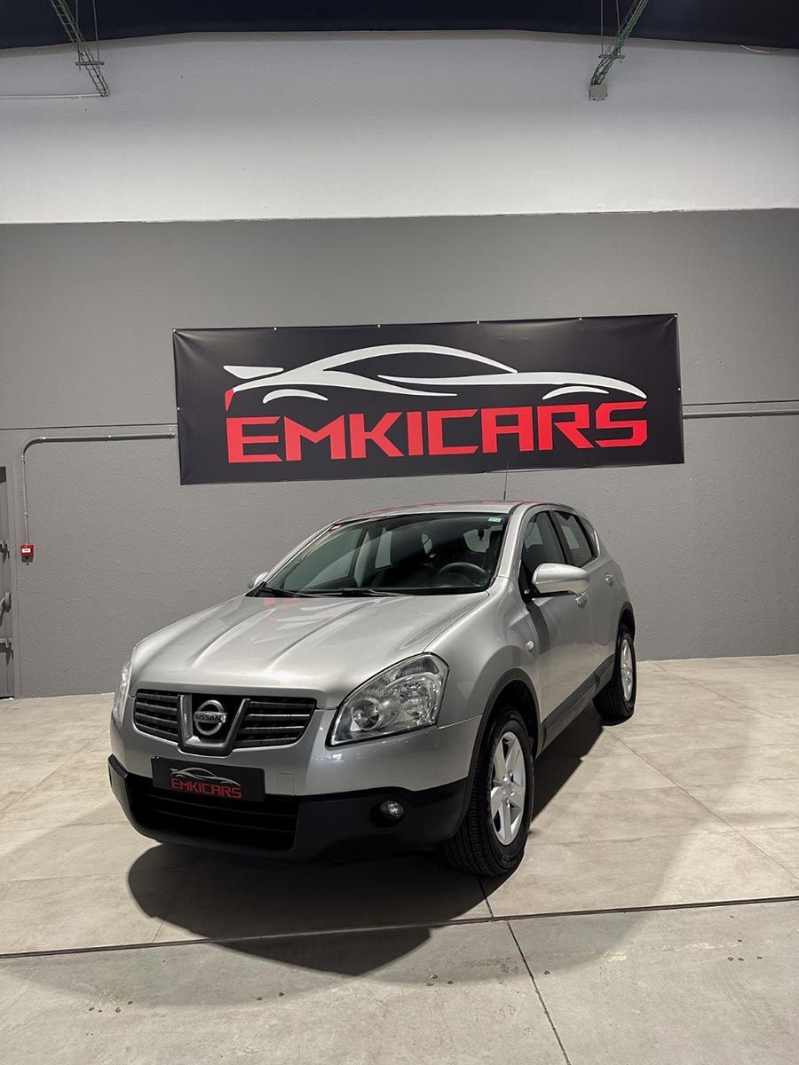 SUV Nissan plateado exhibido en el interior frente a una pancarta de EMKCARS.