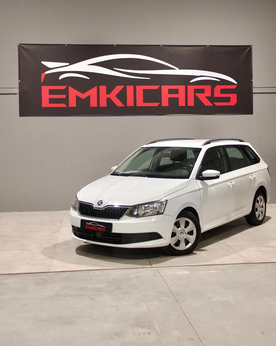 Un familiar blanco en una sala de exposición con un letrero de EMKICARS en la pared.
