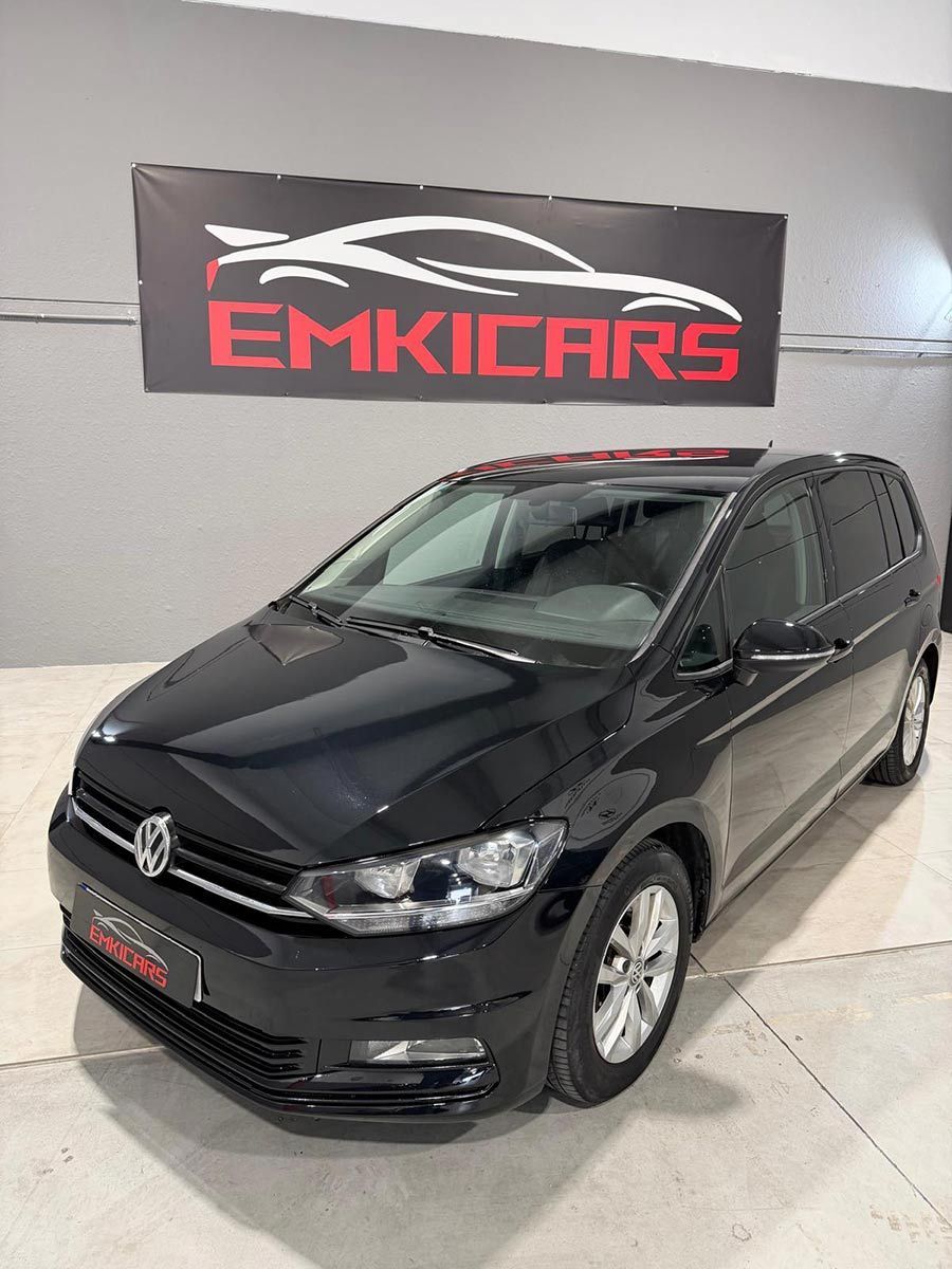 SUV Volkswagen negro en la sala de exposición de un concesionario con un letrero de EMKICARS al fondo.