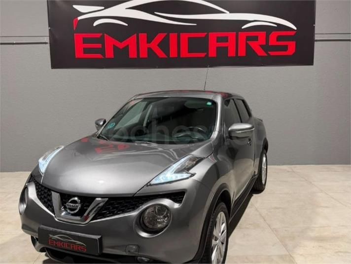 SUV Nissan gris en exhibición en la sala de exposición de un concesionario con un letrero de EMKICARS detrás.