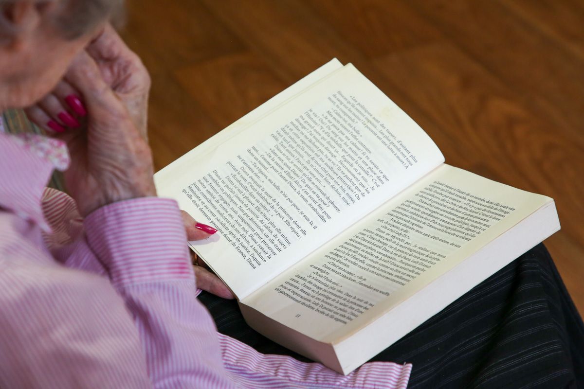 Une dame âgée lit un livre en maison de retraite