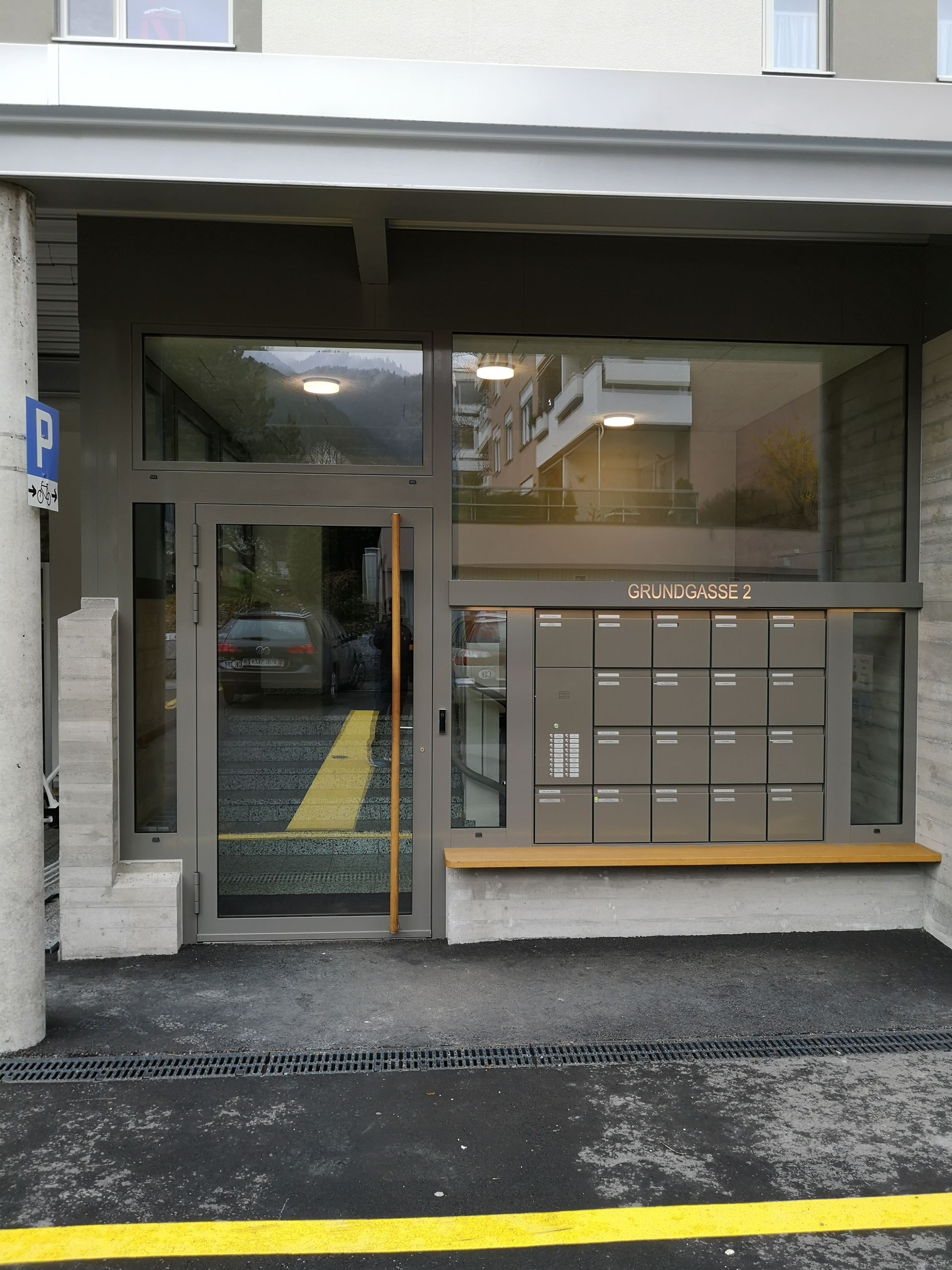 Eingang zum Mehrfamilienhaus mit Glastür und Briefkästen unter einer überdachten Markise