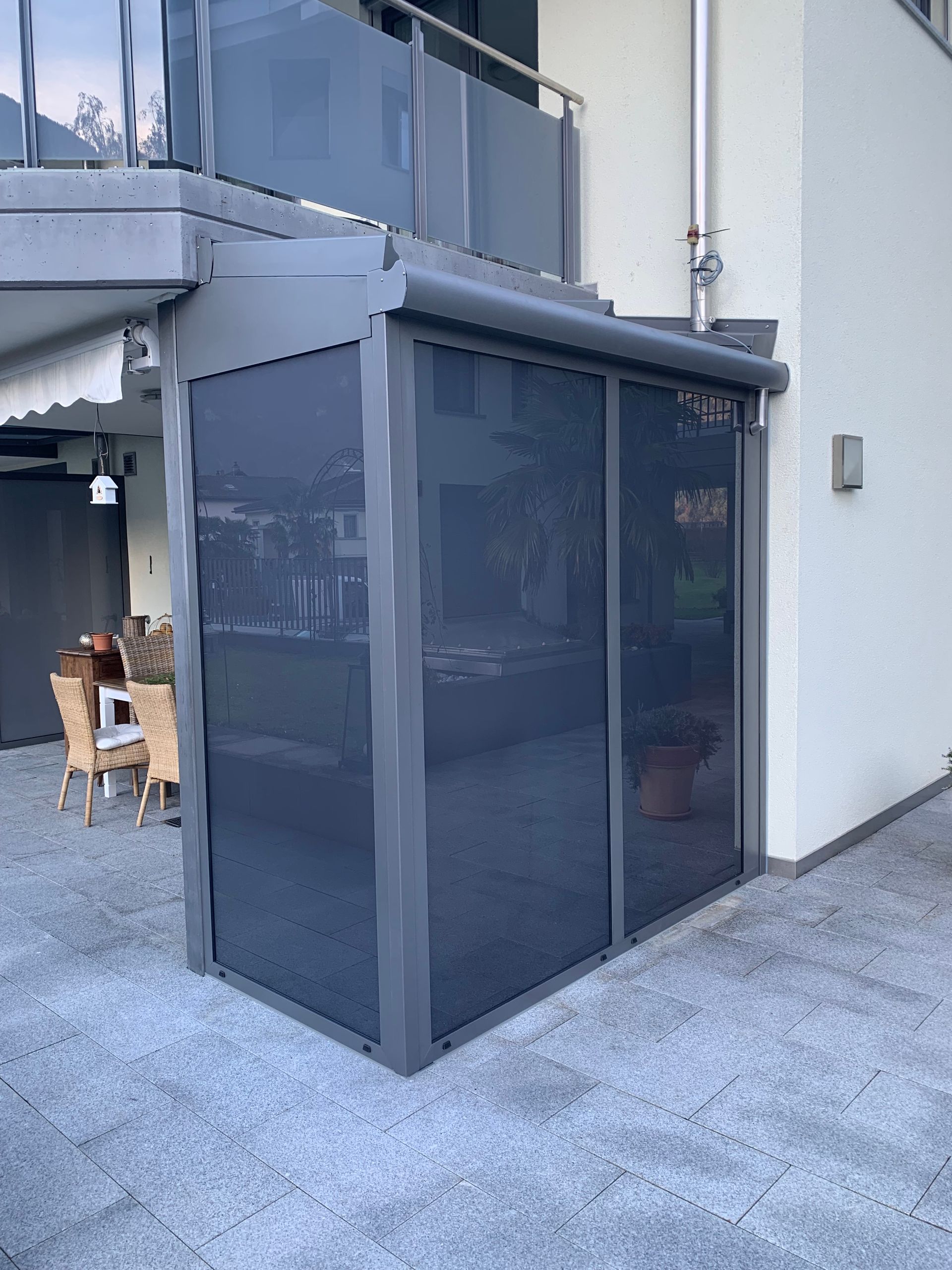 Kleines, dunkelgraues, geschlossenes Bauwerk neben einem Treppenhaus auf einer Betonterrasse