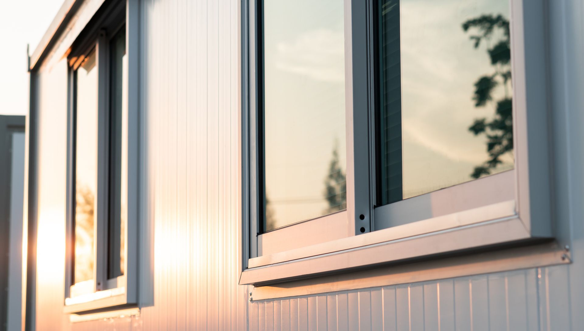 Sonnendurchflutete Fassade eines modernen Gebäudes mit grossen Fenstern und heller Verkleidung.