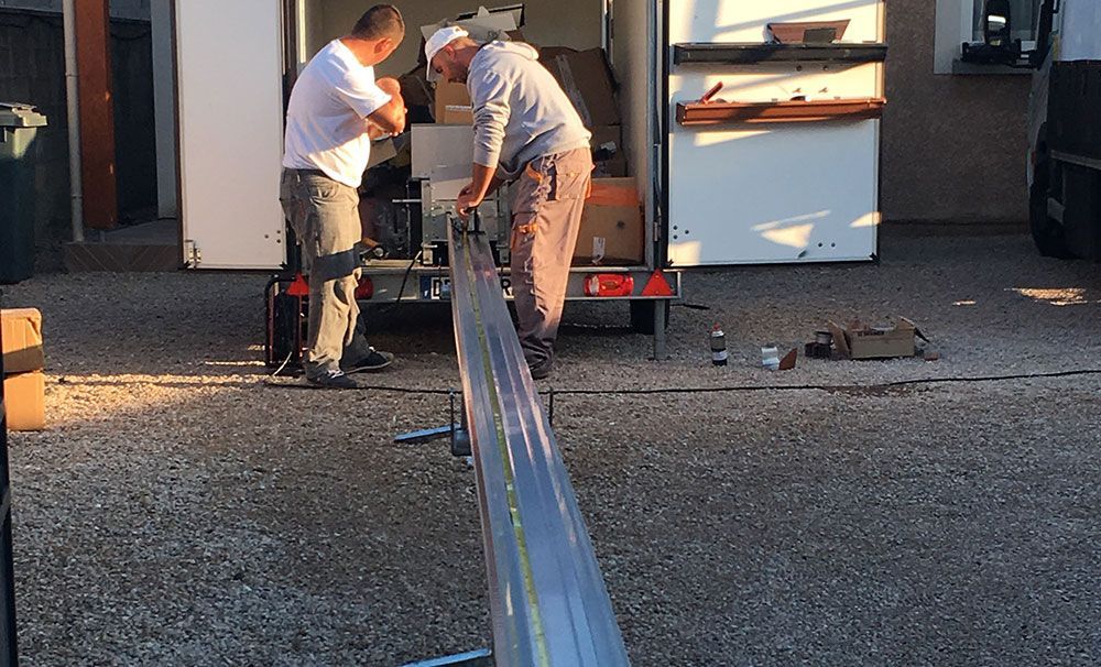 Deux ouvriers qui façonnent une gouttière sans soudure