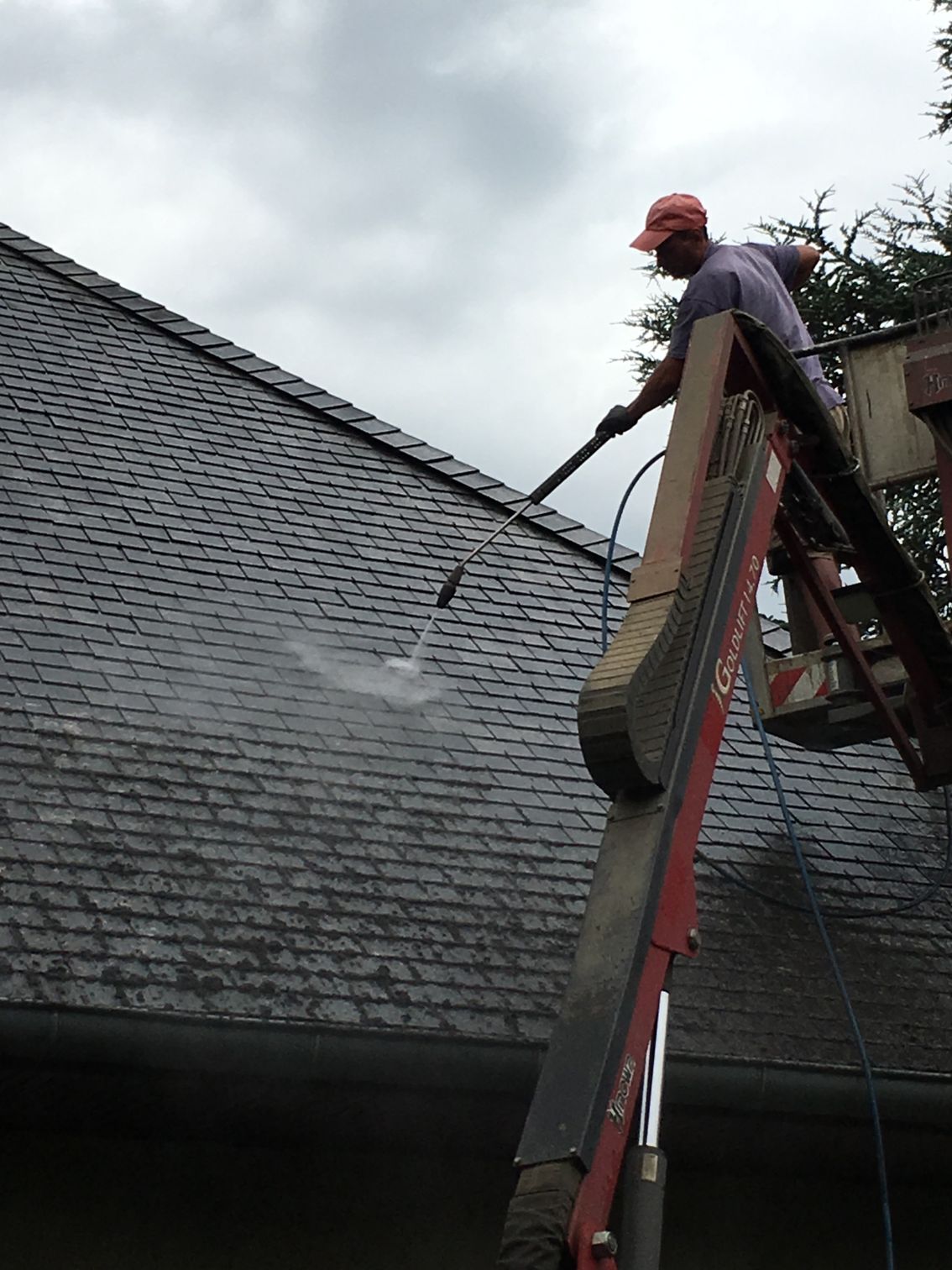 Émoussage d'une toiture par un homme dans une nacelle