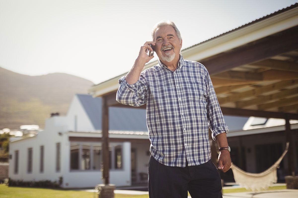 Un homme âgé qui téléphone devant sa maison