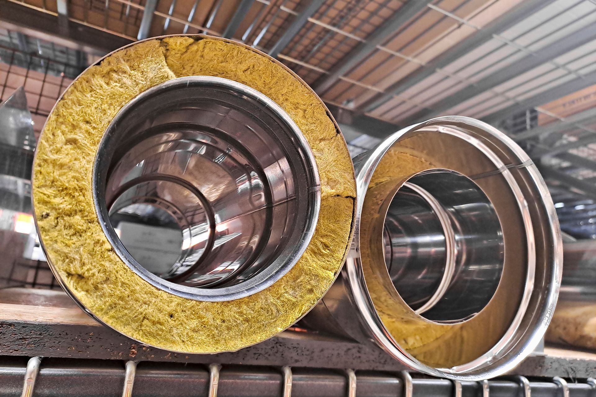 Coupe transversale de deux tuyaux métalliques isolés, montrant les couches de métal, d'isolant et de revêtement extérieur.