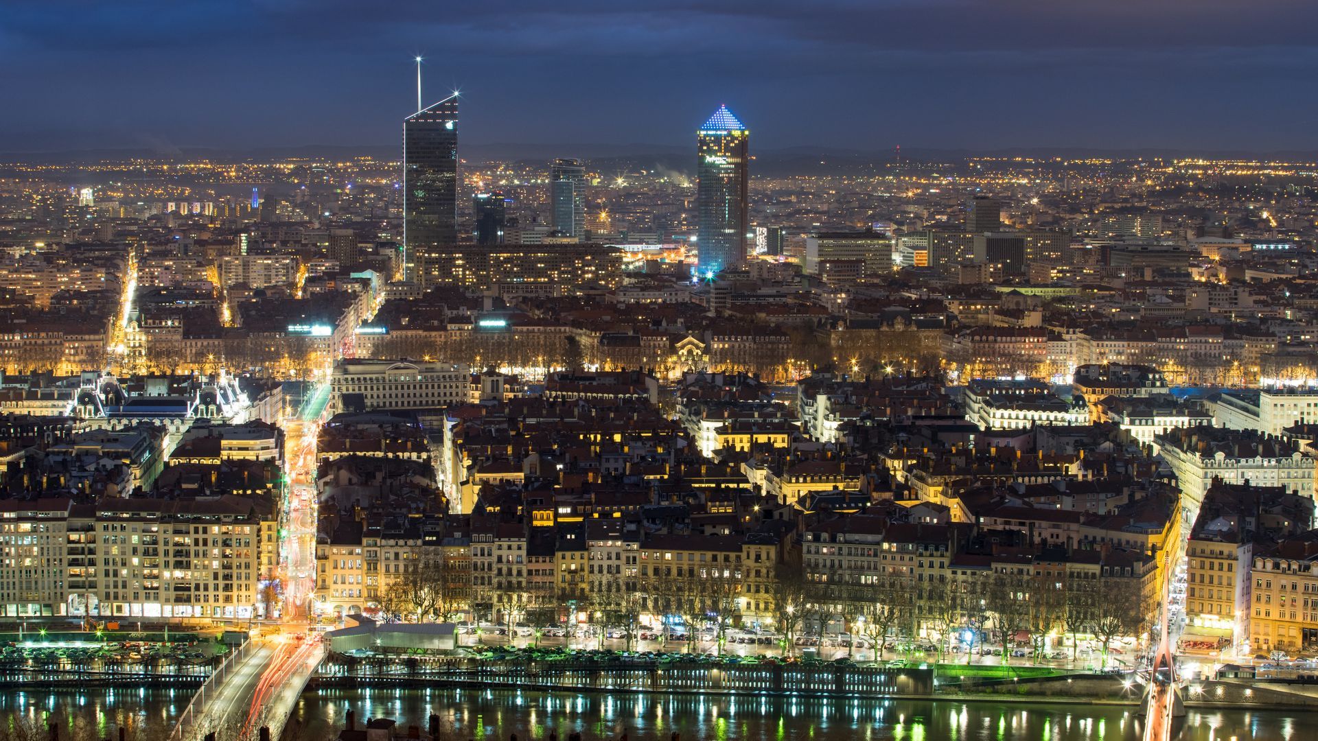 La silhouette de Lyon la nuit, avec ses bâtiments illuminés et deux gratte-ciel imposants.