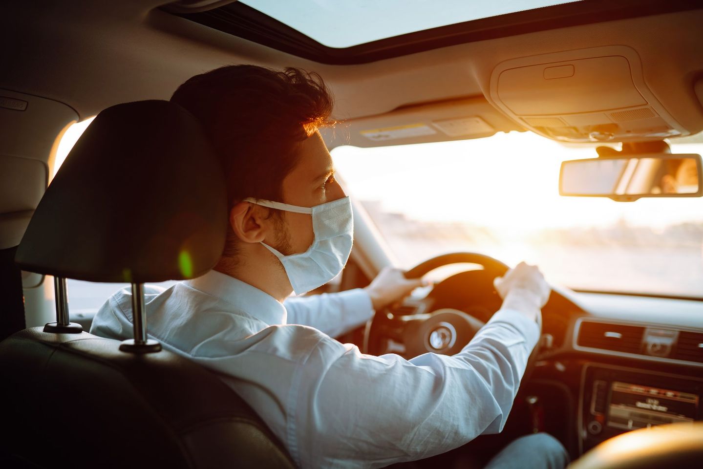 Un homme conduit avec un masque et les mains sur le volant