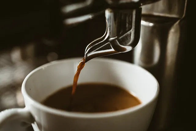 Se vierte una taza de café de una máquina de café a una taza.