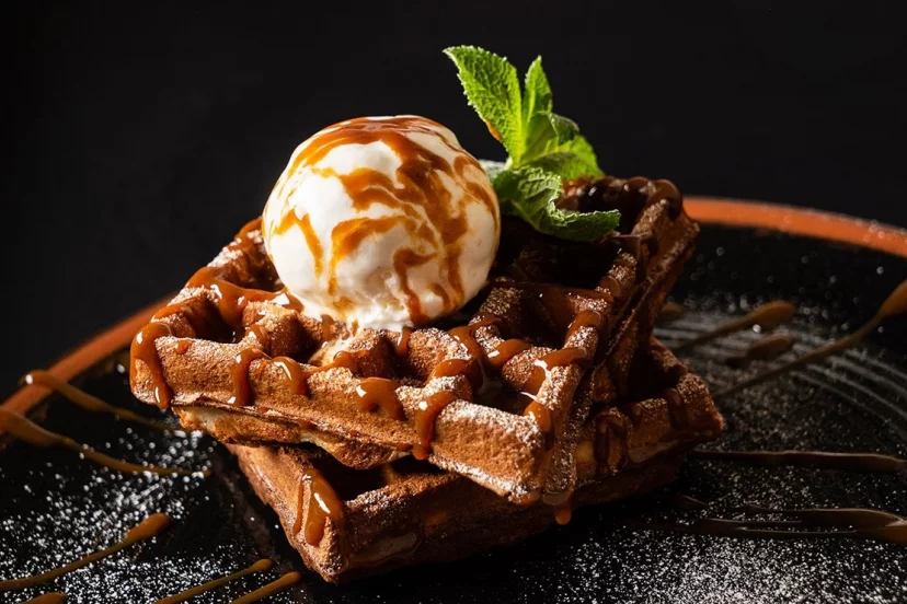 Un gofre de chocolate con helado y salsa de caramelo encima.