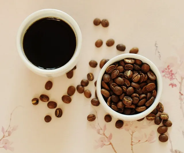 Dos tazas de café y un tazón de granos de café sobre una mesa.
