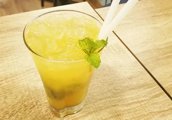 Un vaso de limonada con hielo y una pajita sobre una mesa.