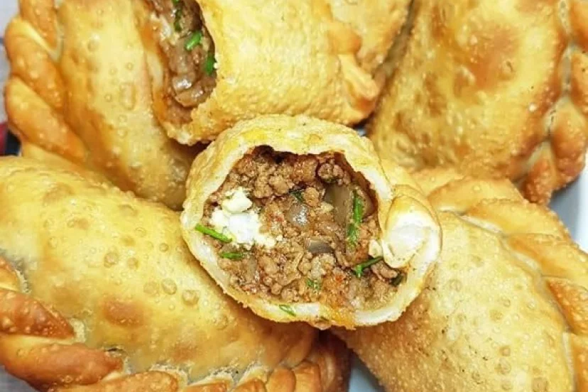 Un primer plano de pasteles fritos con carne y queso en un plato.