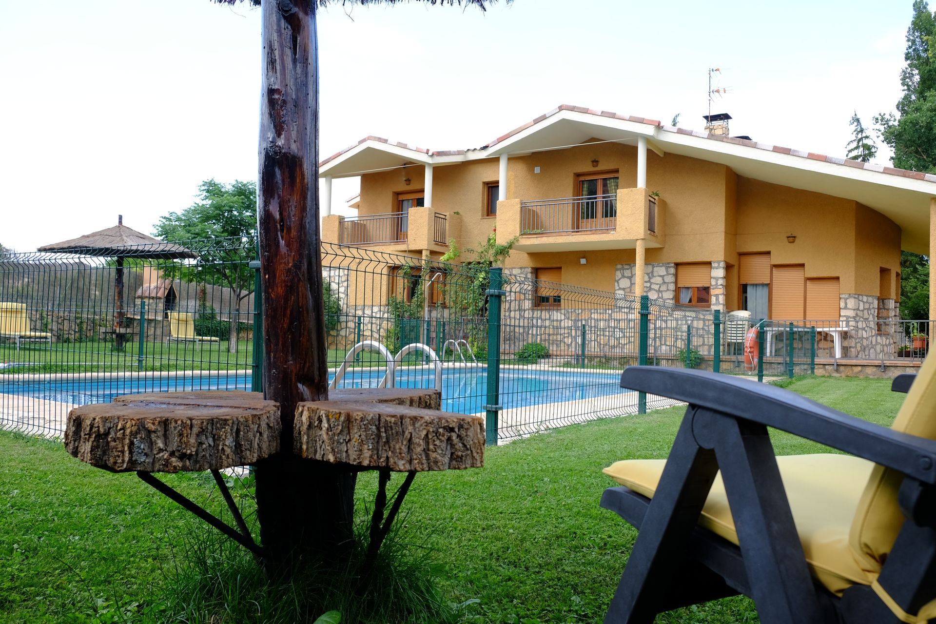 Una casa con piscina y tumbonas de madera en un día soleado.