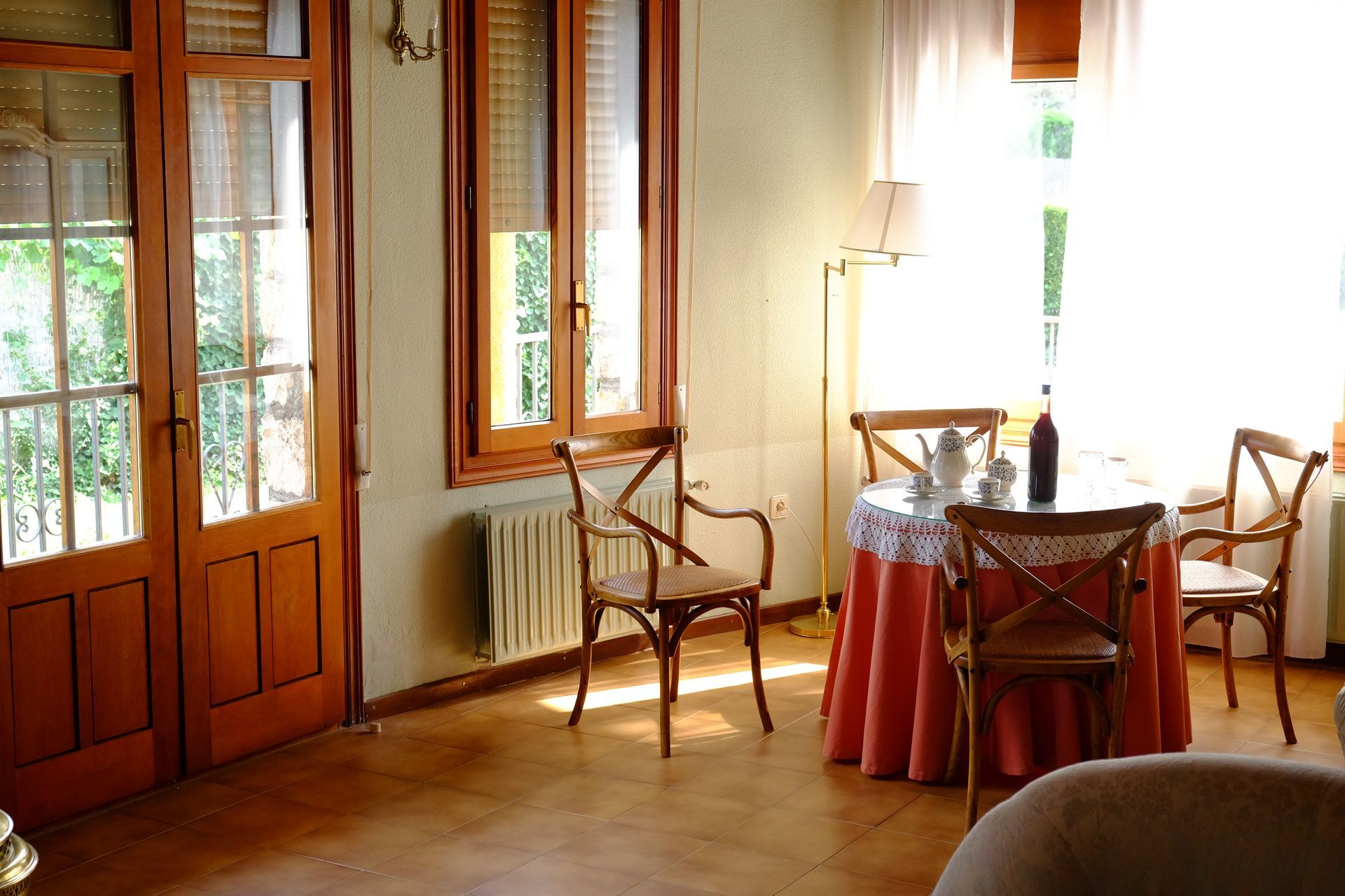 Comedor con mesa redonda, sillas y puertas francesas. La luz natural inunda el espacio.