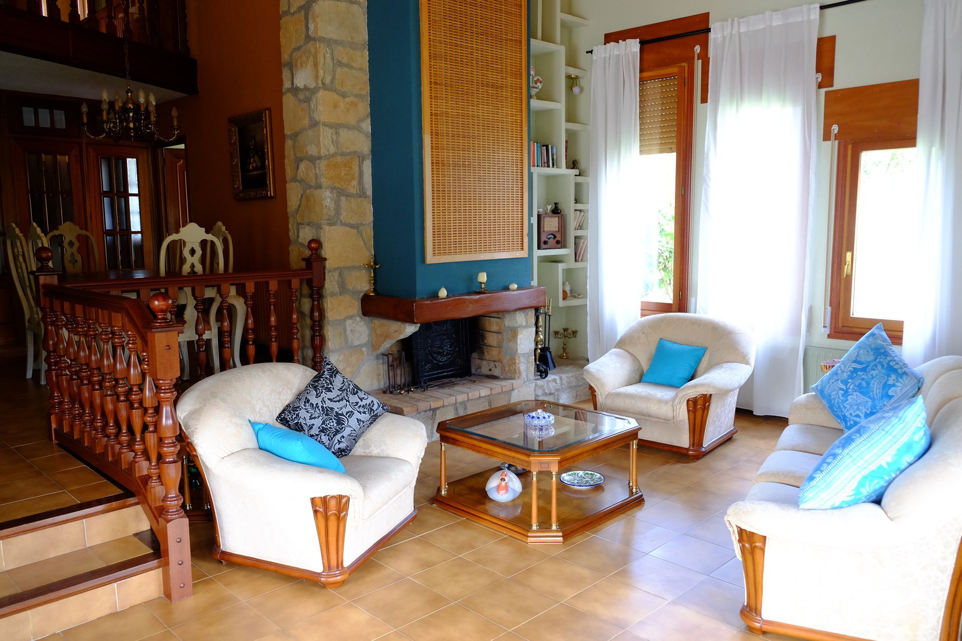 Sala de estar con chimenea, sofás blancos, almohadas azules y muebles de madera.