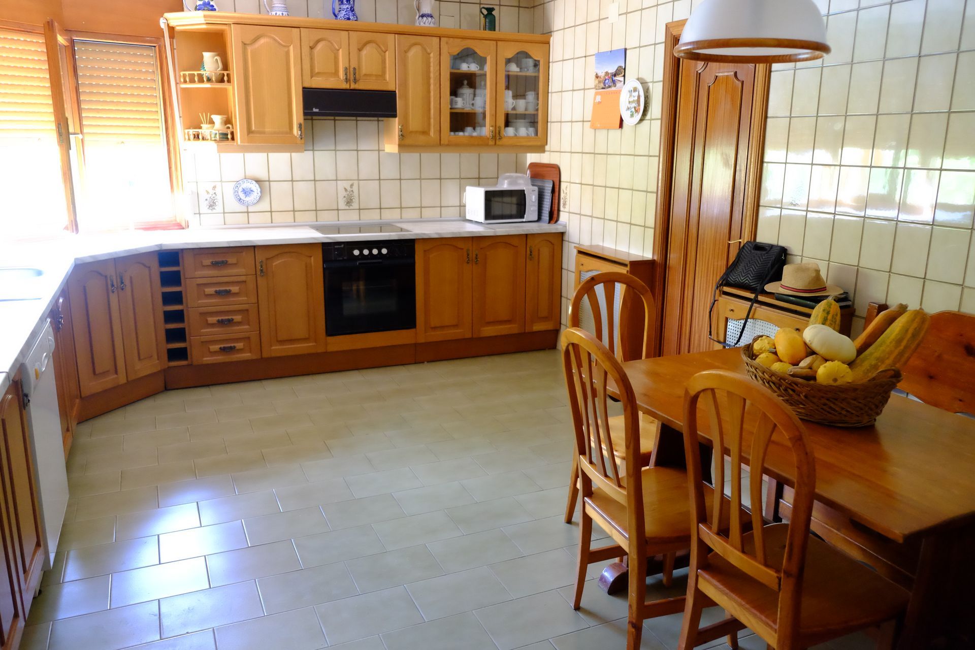 Cocina con gabinetes de madera, electrodomésticos y mesa de comedor con sillas.