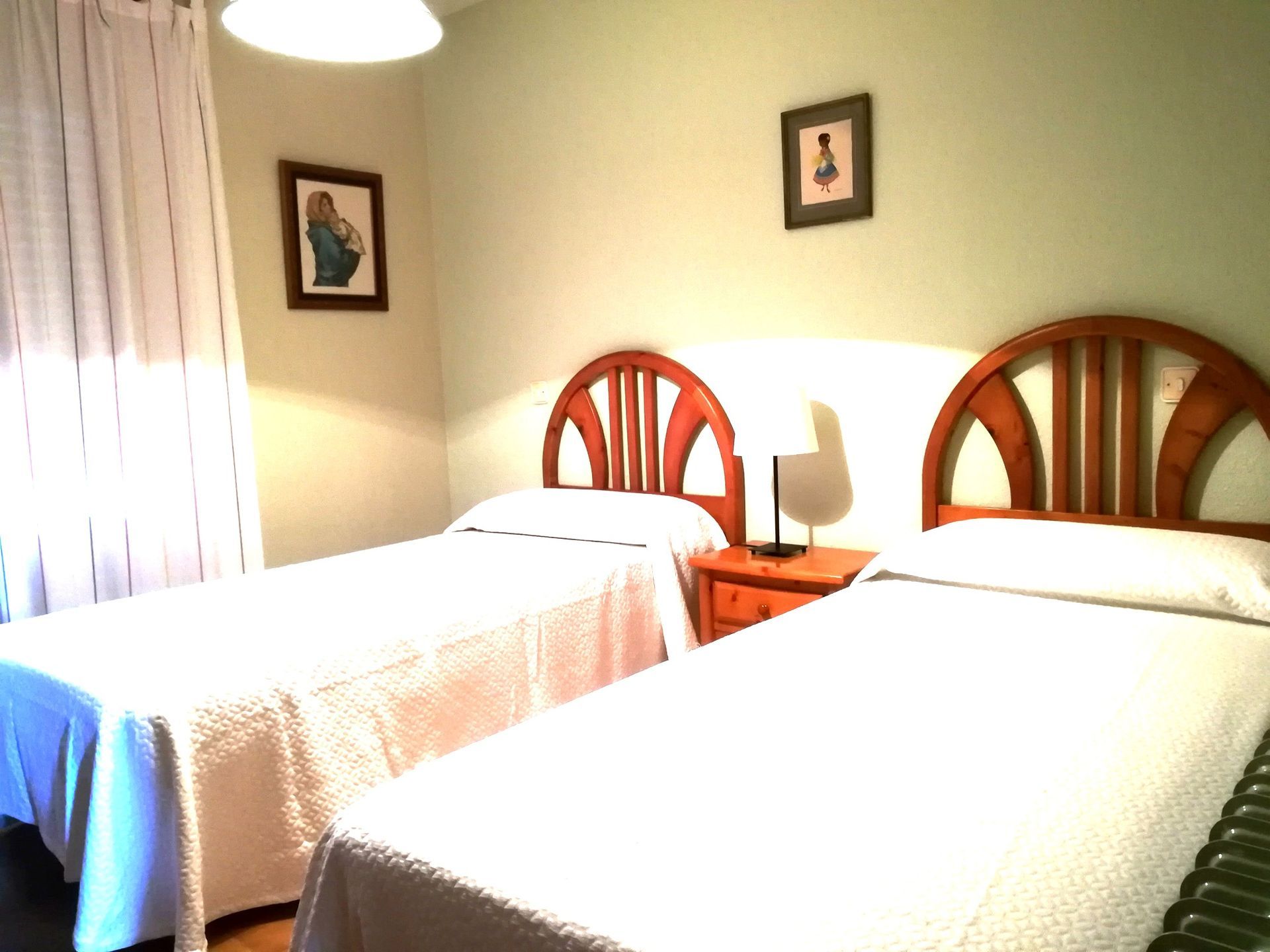 Camas individuales en un dormitorio con cabeceros de madera, mesita de noche y arte de pared.