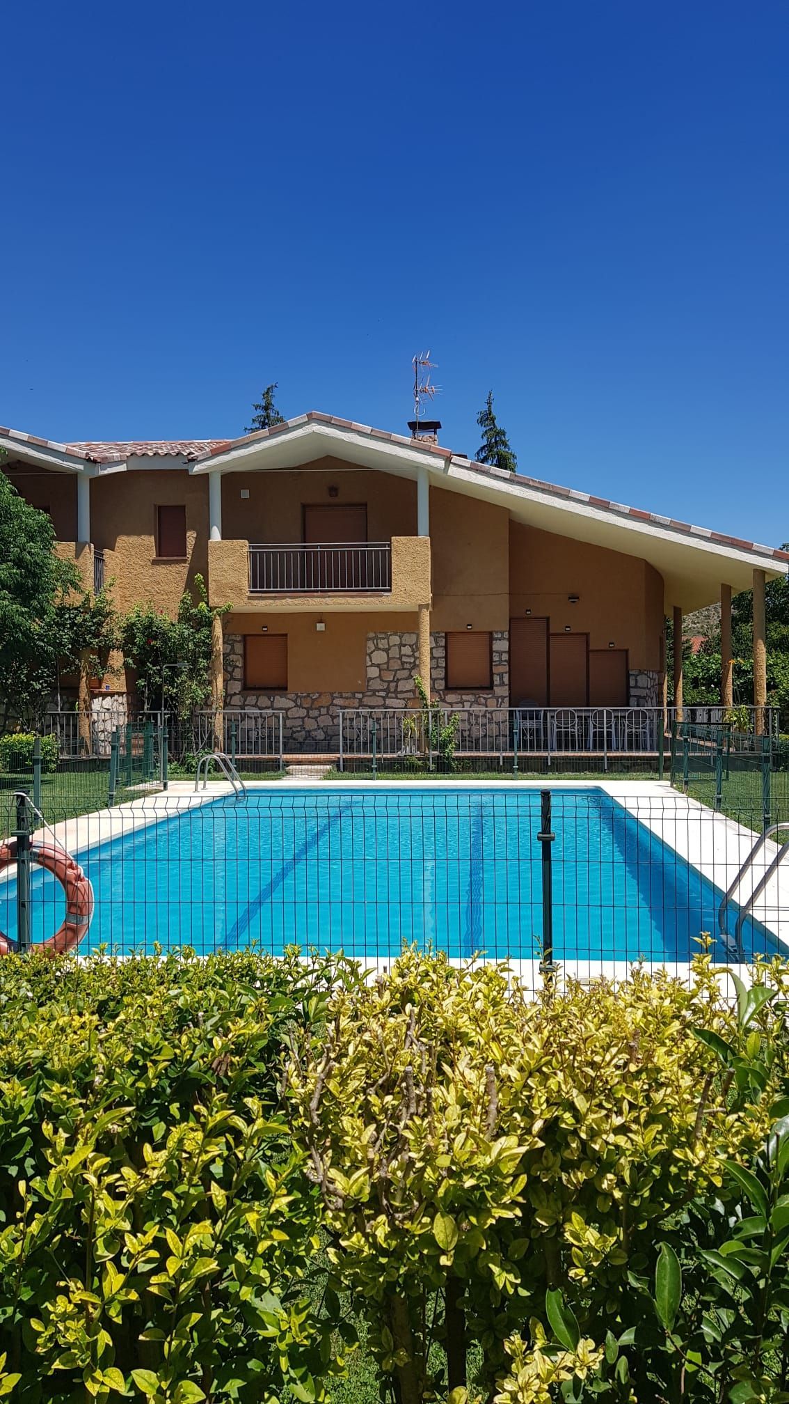 Casa con piscina en un día soleado. Agua turquesa, exterior bronceado y cielo azul.