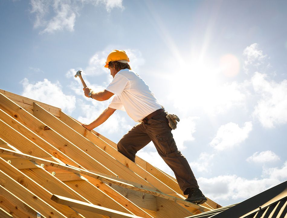 Ouvrier debout sur une charpente tenant un marteau dans la main