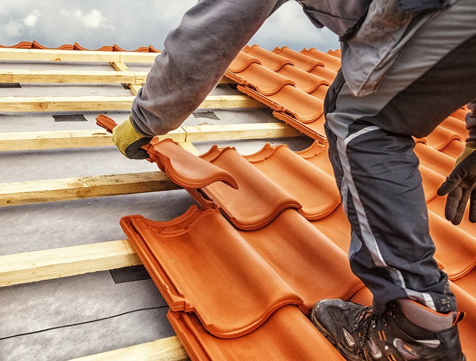 Ouvrier posant des tuiles neuves sur une toiture