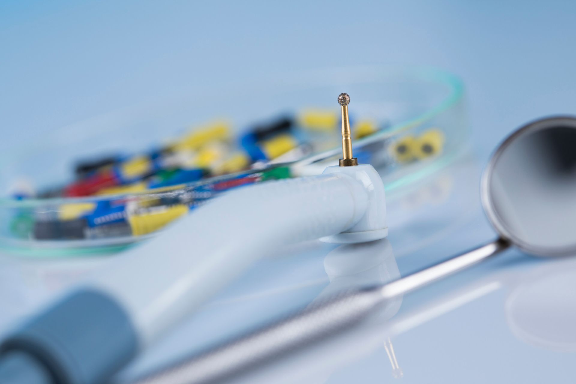 Niño sonriendo durante una revisión dental; las manos del dentista con herramientas visibles.