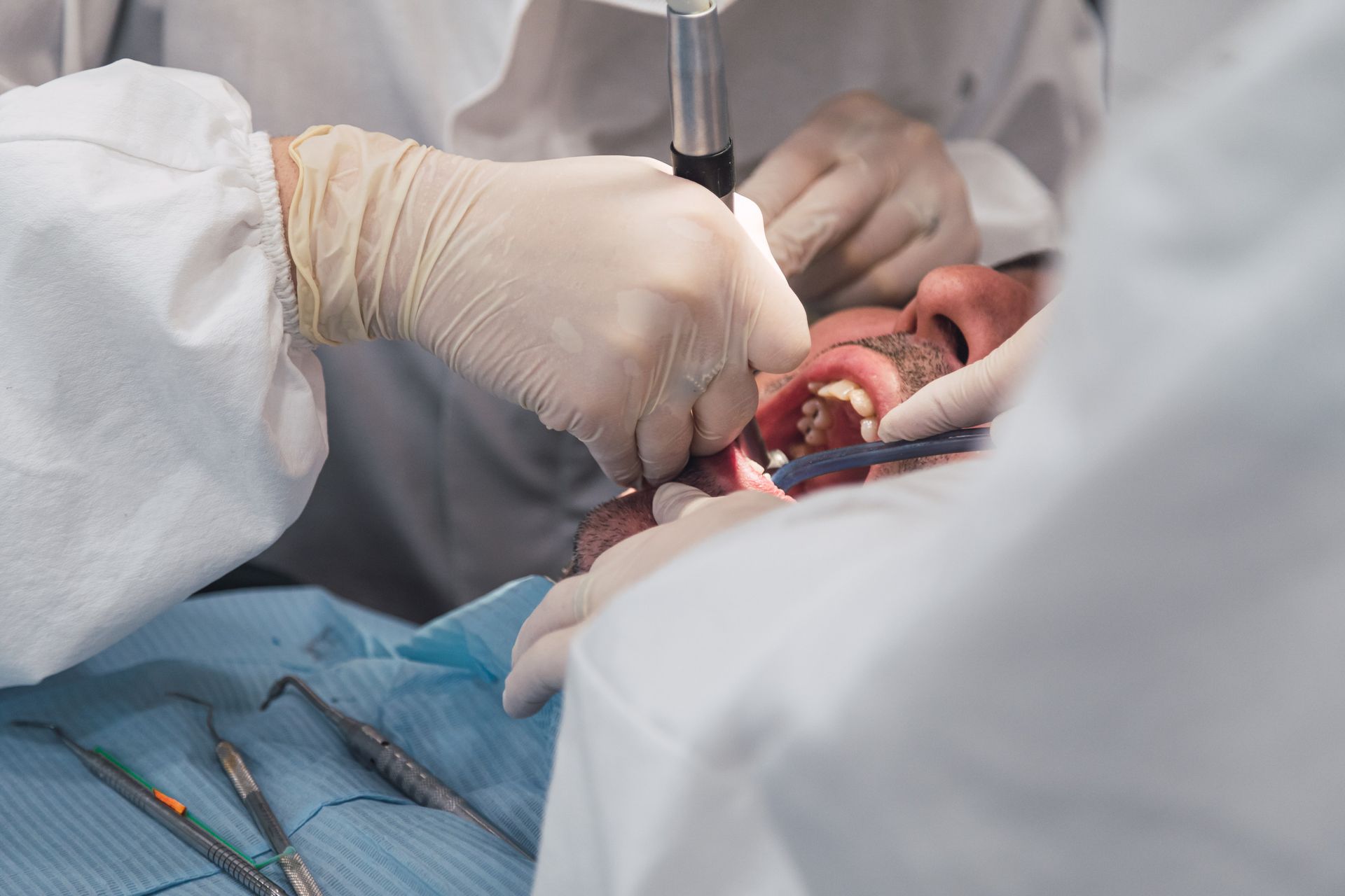 Dentista examinando la boca abierta de un paciente con herramientas en un entorno clínico.