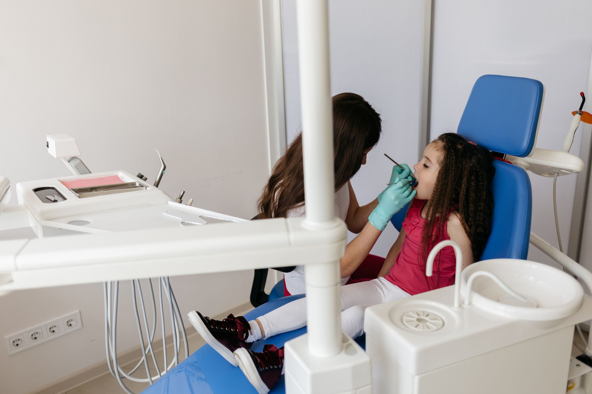 Dentista examinando la boca abierta de un paciente con herramientas en un entorno clínico.