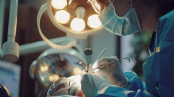 Dentista realizando un procedimiento en los dientes del paciente bajo luces brillantes.