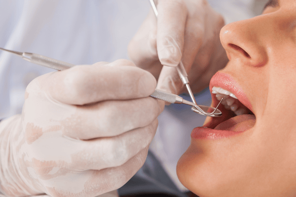 Dentista examinando los dientes del paciente con instrumentos dentales.