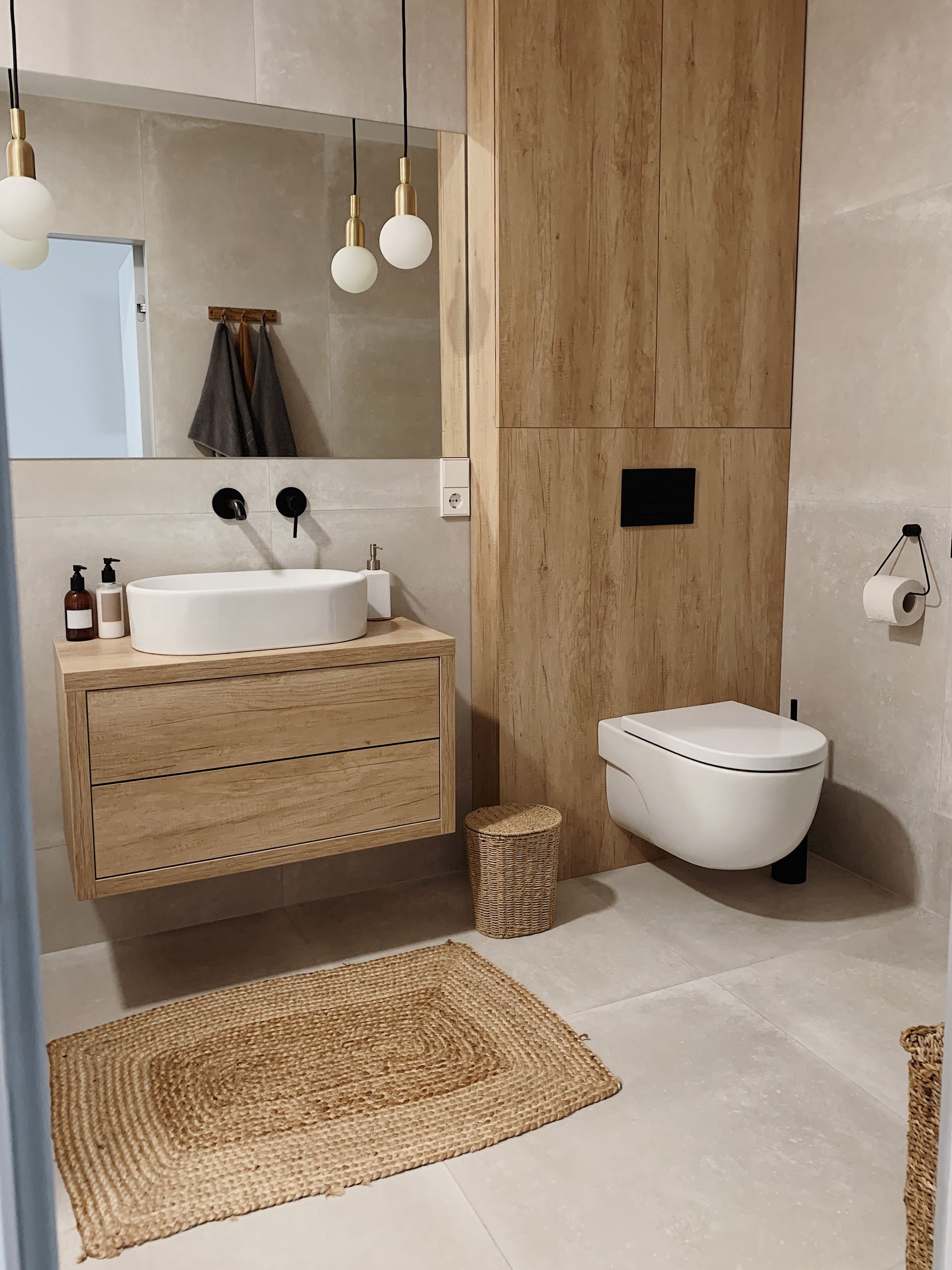 Salle de bains moderne avec lambris, meuble-lavabo suspendu, robinetterie blanche et tapis tissé.