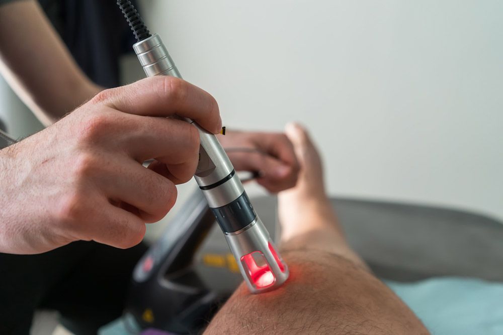 Terapia láser aplicada a la rodilla de una persona. Luz láser roja visible.