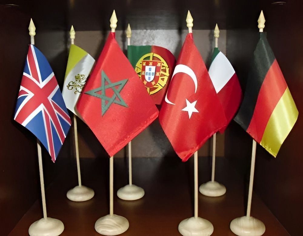 Seis banderas izadas en mástiles, entre ellas las del Reino Unido, Marruecos, Portugal, Turquía, Italia y Alemania.
