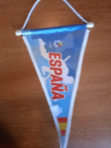 Banderín azul de España con ribete blanco colgado sobre una superficie de madera.