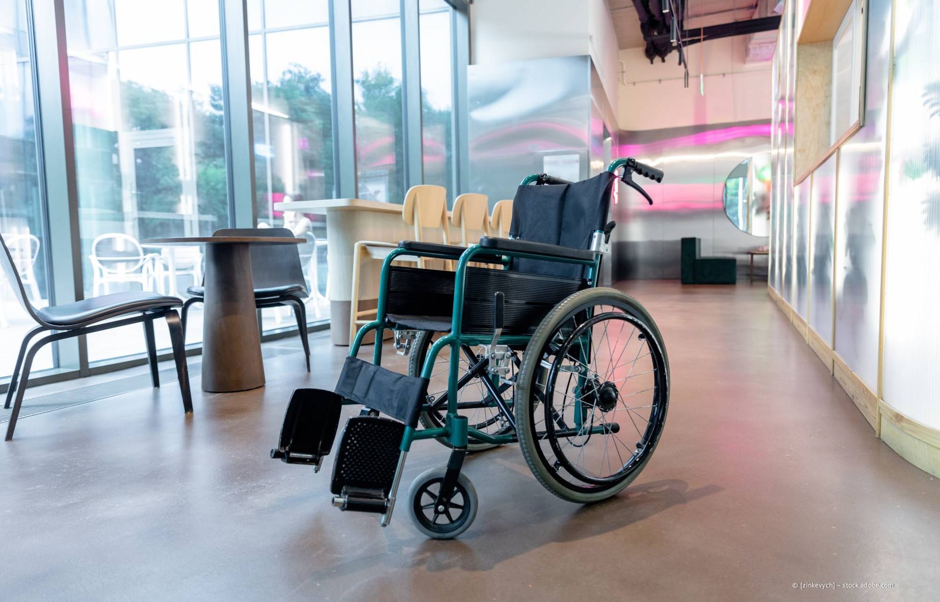 Rollstuhl in einem modernen Gebäude mit Tischen und Fenstern.