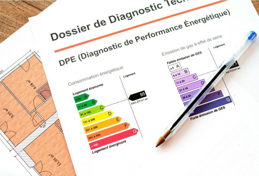 Un rapport sur l'efficacité énergétique du DPE repose sur une table en bois, à côté d'un plan d'étage et d'un stylo à bille bleu.