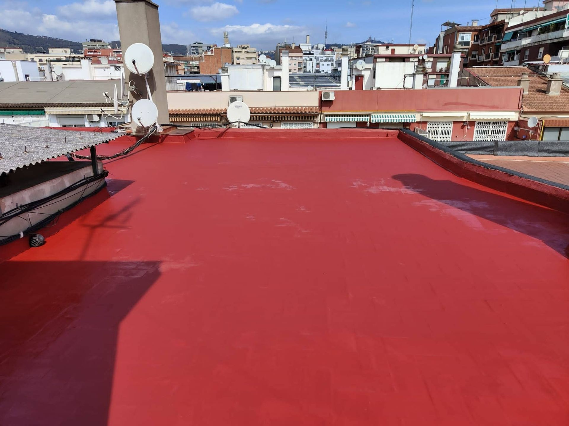 Un techo rojo con muchos edificios al fondo.