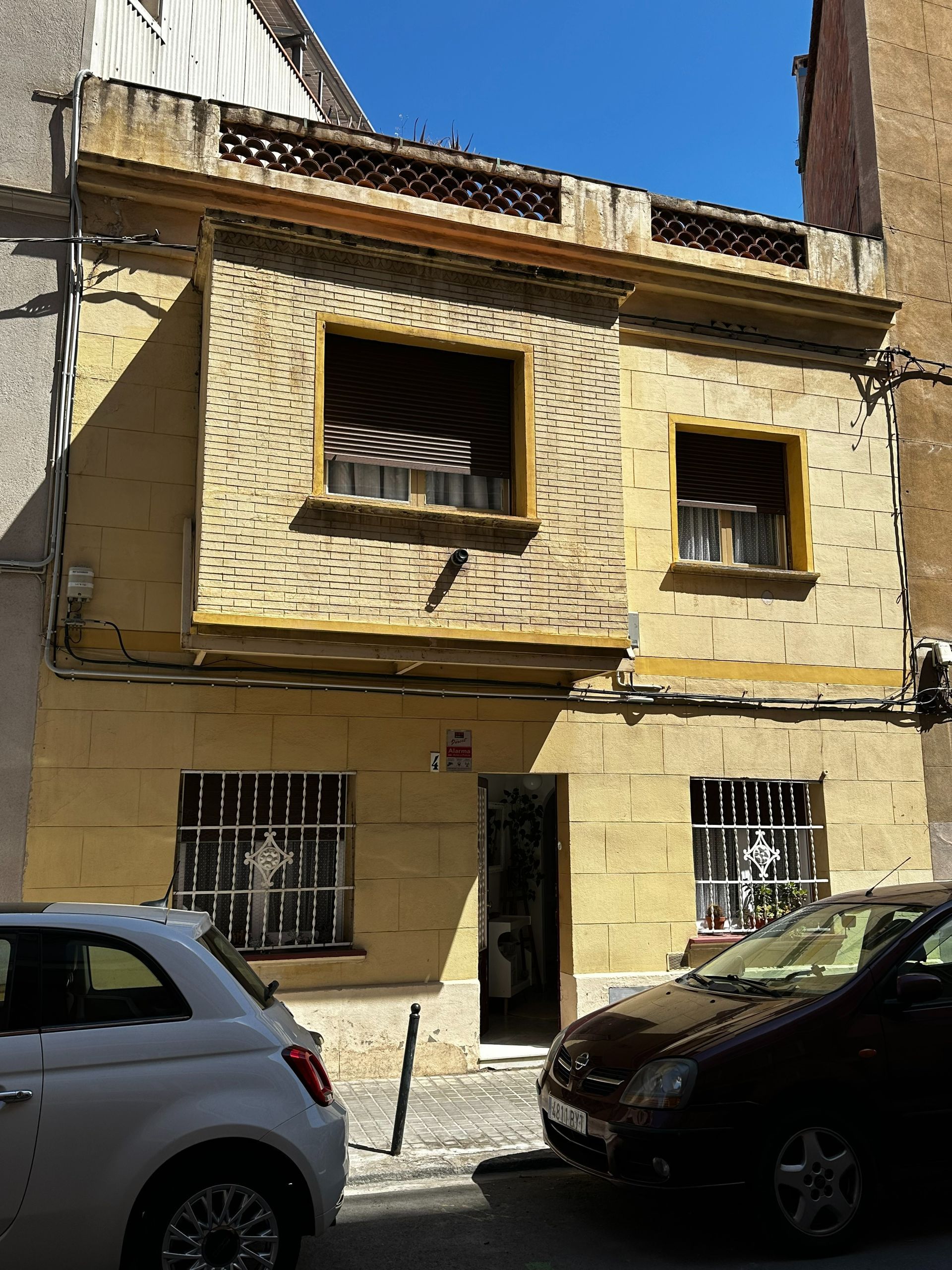 Un coche blanco está aparcado delante de un edificio amarillo.