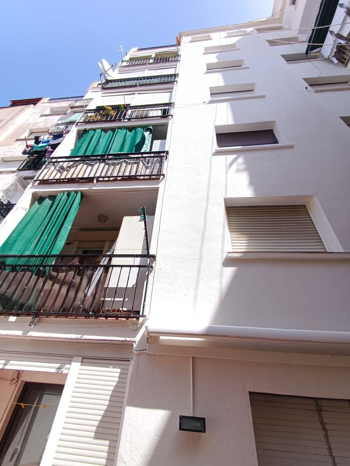 Mirando hacia arriba a un edificio blanco con balcones y persianas