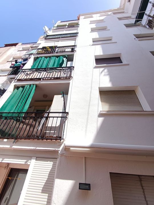 Mirando hacia arriba a un edificio blanco con balcones y persianas