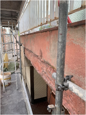 Una escalera está colocada encima de un andamio al lado de un balcón.