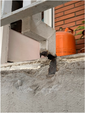 Una pared de ladrillos con una barandilla blanca y una bombona de gas naranja.